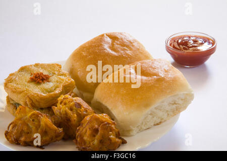 Indian fast food patate fritte o batata vada kanda bhaji e bun pav servita con il ketchup nella piastra ; India Foto Stock