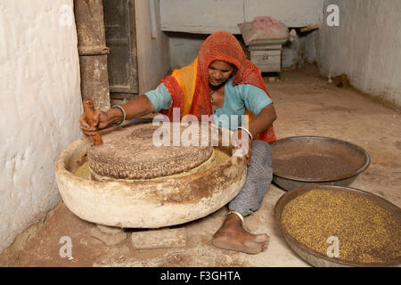 Una donna usando pietra mola per dividere seme di senape prima di mettere in pressione olio di frantoio; Rajasthan ; India Foto Stock