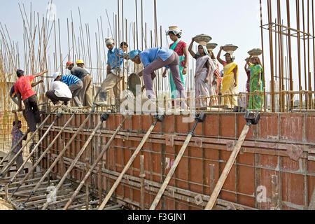 Operai di costruzione impegnati nell'attività di riempimento della lastra concreta in un luogo di costruzione in Ahmedabad ; Gujarat ; India ; operai indiani Foto Stock