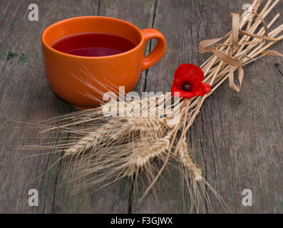 Ancora in vita una tazza di argilla con succo, frumento e un fiore di papavero Foto Stock