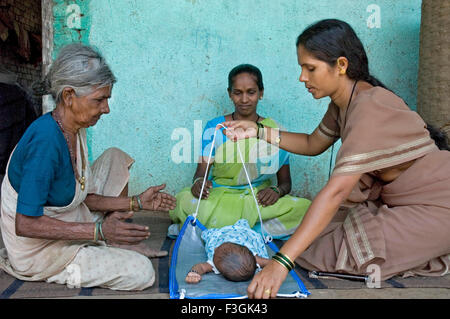 Salute della donna volontario spiegando village 'dai' ostetrica tradizionale Bilancia Peso monitor neonato Thane Mumbai India Foto Stock