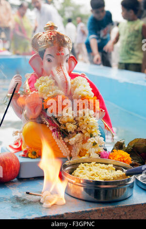 Piccolo idolo del signore ganesh elephant intitolata Dio pronto a immerso con piccoli incendi e offerta di dolci di fronte ; Pune Foto Stock