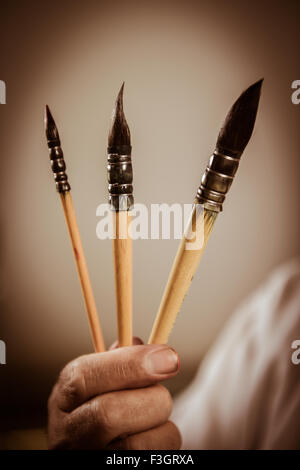 La mano del pittore azienda tre pennelli Foto Stock