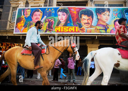 Il fornitore di cavalli Bollywood di fronte al poster del film di Bollywood all'Alfred Cinema Grant Road Bombay Mumbai Maharashtra India Foto Stock