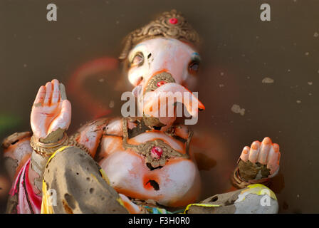 Ganesh idolo giacente in acqua inquinata dopo immersione sulla spiaggia Aksa ; Mumbai Bombay ; Maharashtra ; India Foto Stock