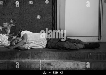 Un senzatetto uomo addormentato in negozio porta nel centro di Berlino. Foto Stock