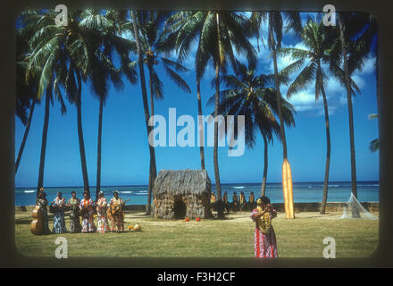 I turisti frequentano un Luau delle Hawaii durante gli anni cinquanta con intrattenimento da hawaiiani. ballerina di hula hut Foto Stock