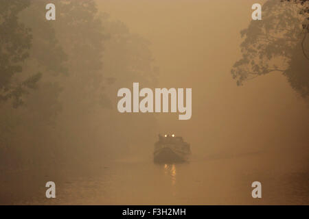 (151007) -- a sud di Sumatra, il 7 ottobre 2015 (Xinhua) -- una barca con vele di luci su aria Sugihan fiume amid thick haze in Ogan Komering Ilir, a sud di Sumatra, Indonesia, il 7 ottobre 2015. Smokey haze da piantagione e di incendi di foreste in Indonesia hanno raggiunto Singapore e Malesia, causando le scuole a chiudere e voli per essere distrutti in quello che è diventato un punto annuale delle tensioni tra i paesi. (Xinhua/Nova Wahyudi) Foto Stock