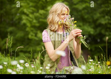 Donna matura in giardino, profumati fiori Foto Stock