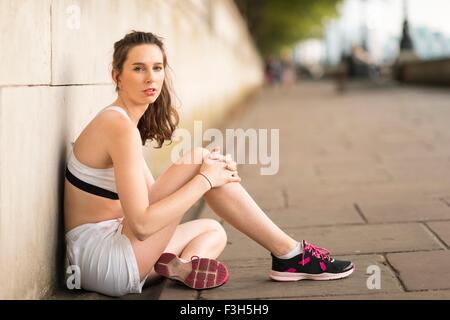 Ritratto di giovane donna seduta runner su Riverside Foto Stock