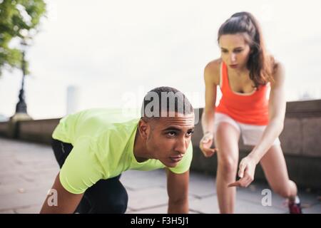 Giovane allenatore femmina con maschio runner su riverbank Foto Stock