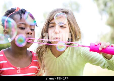 Le ragazze a soffiare bolle in posizione di parcheggio Foto Stock