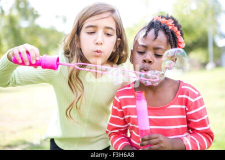 Le ragazze a soffiare bolle in posizione di parcheggio Foto Stock