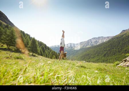 Giovane donna facendo handstand, Val Senales Alto Adige - Italia Foto Stock