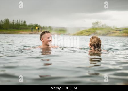 Coppia giovane rilassante in Laguna Segreta primavera calda (Gamla Laugin), Fludir, Islanda Foto Stock