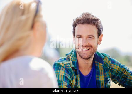 Sulla spalla vista di metà uomo adulto seduto sorridente al giovane donna Foto Stock