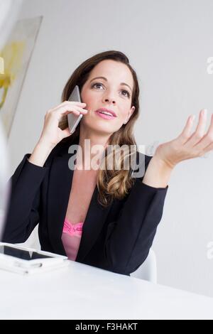 Donna matura utilizza lo smartphone gesticulating Foto Stock