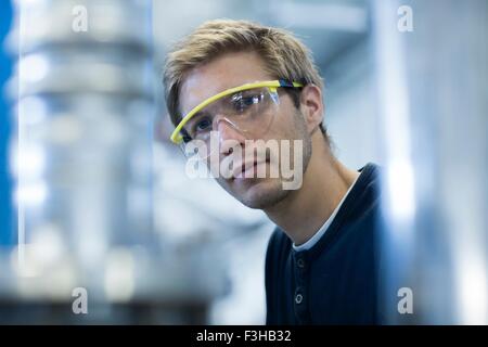 Ritratto di ingegnere in fabbrica che indossa gli occhiali di protezione Foto Stock