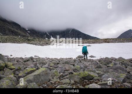 Vista posteriore del giovane maschio escursionista che guarda al lago ghiacciato, monti Urali, Russia Foto Stock