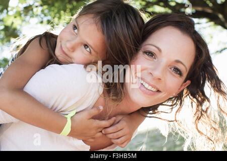 Ritratto di donna matura dando figlia piggy back in posizione di parcheggio Foto Stock