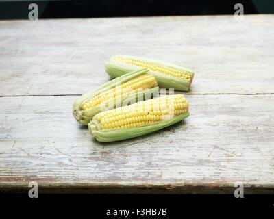 Ancora la vita di tre nuovi tutoli di mais sul tavolo di legno Foto Stock