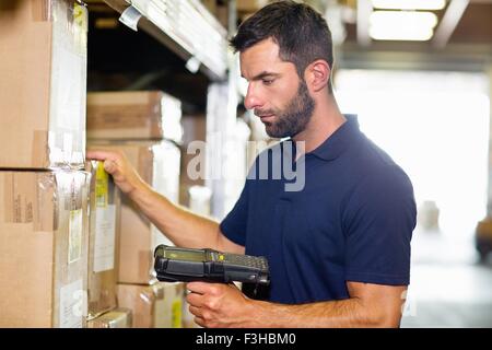 Lavoratore di magazzino utilizzando uno scanner di codici a barre nel magazzino di distribuzione Foto Stock