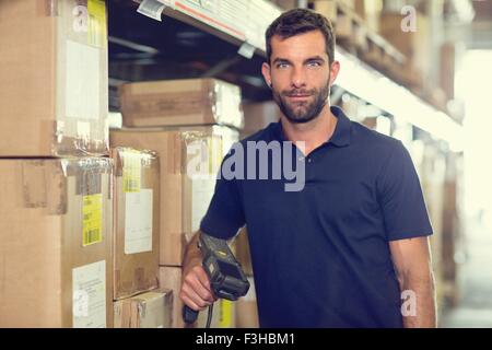 Ritratto di lavoratore di magazzino utilizzando uno scanner di codici a barre nel magazzino di distribuzione Foto Stock