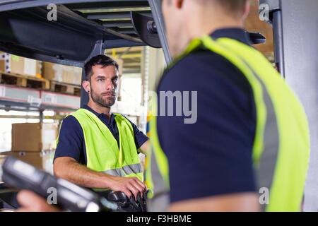 Supervisor istruire il carrello elevatore a forche driver nel magazzino di distribuzione Foto Stock