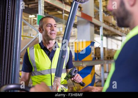 Supervisore maschio istruire il carrello elevatore a forche driver nel magazzino di distribuzione Foto Stock