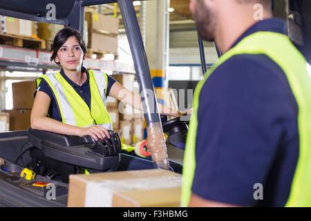 Supervisore femmina istruire il carrello elevatore a forche driver nel magazzino di distribuzione Foto Stock