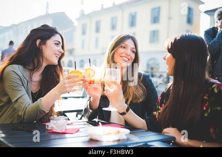 Tre giovani donne elevare un toast al cafè sul marciapiede Foto Stock