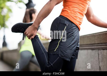 Maschio e femmina guide città stretching gambe Foto Stock