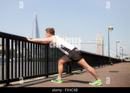 Runner stretching sul lungofiume, Wapping, Londra Foto Stock