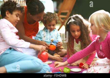 Madre e quattro bambini che giocano un pic-nic in giardino festa di compleanno
