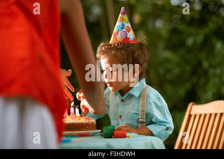 Madre e figlio soffiando candele sulla torta di compleanno in giardino festa di compleanno