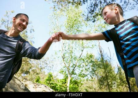 Escursionista maschio figlio dando una mano in foresta Foto Stock