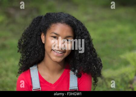 Ritratto di una ragazza con il nero capelli ricci guardando sorridente della fotocamera Foto Stock