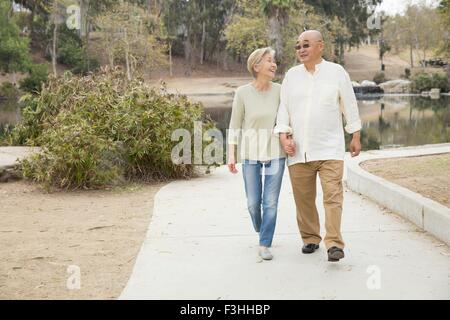 Coppia senior camminando lungo il percorso, tenendo le mani Foto Stock