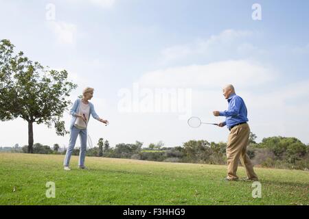 Coppia senior giocando badminton in posizione di parcheggio Foto Stock