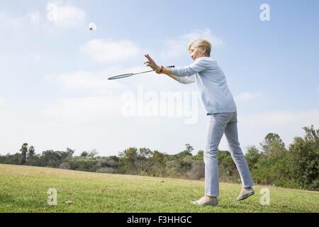 Senior donna riproduzione di badminton in posizione di parcheggio Foto Stock