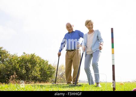 Coppia senior giocando croquet in posizione di parcheggio Foto Stock