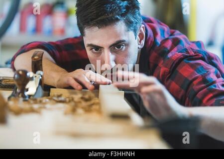 Giovane uomo con piano in legno per levigare legno oggetto Foto Stock