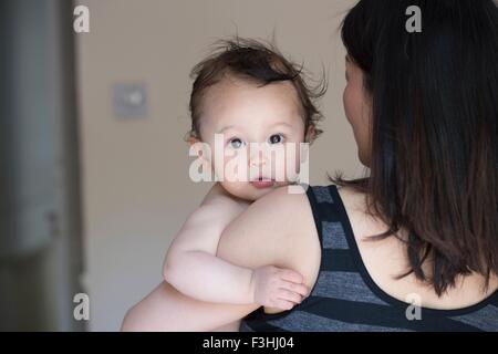 Ritratto di curioso baby boy in coppia i bracci delle madri Foto Stock