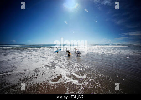 Giovani surfisti dirigendosi verso le onde per il surf Foto Stock