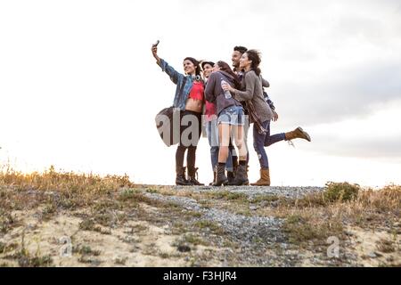 Giovane uomo e quattro sorelle adulte in posa per smartphone selfie su sterrato Foto Stock