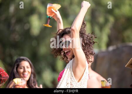 Giovane donna di bere un cocktail e ballare in giardino Foto Stock