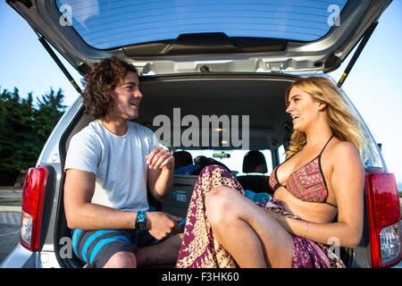 Giovane seduto nel bagagliaio della vettura, faccia a faccia sorridente Foto Stock