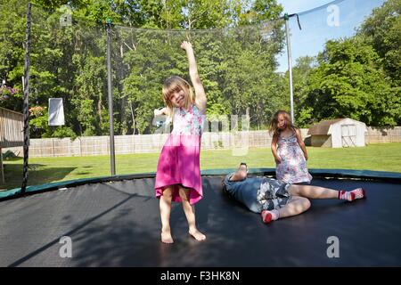 Le tre ragazze giocando sul trampolino in giardino Foto Stock