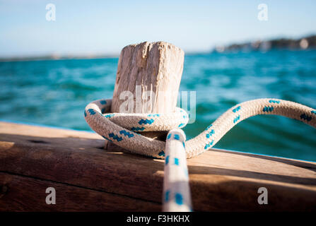 LAMU, Oceano Indiano, Kenya, Africa. Una corda avvolta intorno a un vecchio legno peg su una barca a vela di legno alla deriva in acque blu. Foto Stock