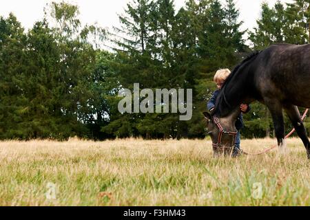 Piccolo Ragazzo con pony nel campo Foto Stock